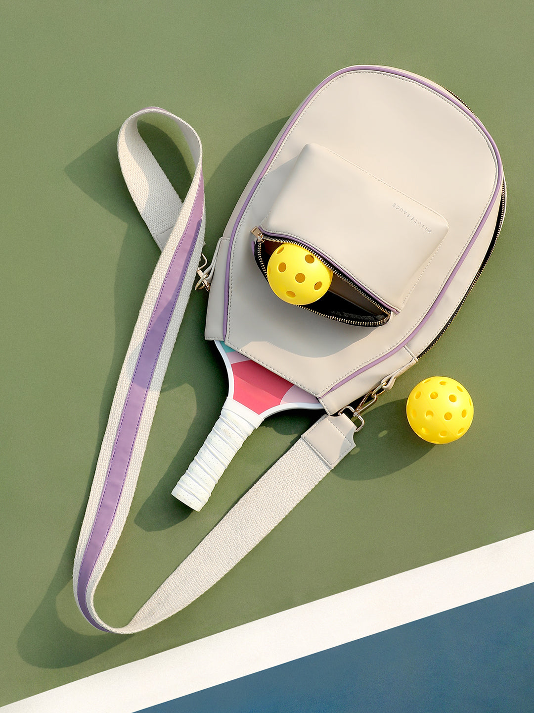 Ivory and purple pickleball crossbody sport bag showing the dedicated front paddle sleeve - Haute Sauce.